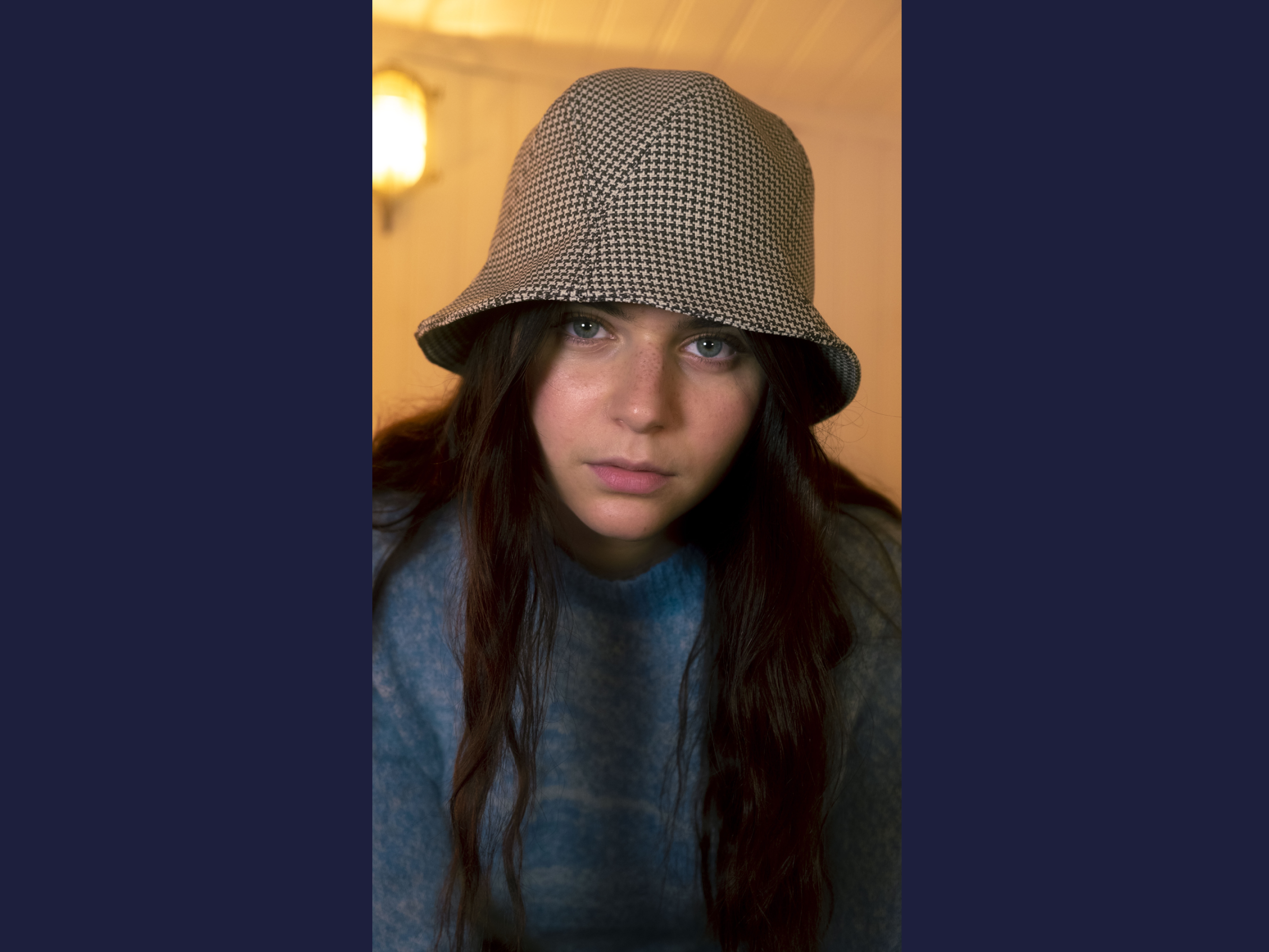Michetti is wearing a Le Panache Paris© bucket hat made in France with Go Couture_61138, Gabriel© brand fabric, 100% Trevira cs, brown houndstooth pattern on a beige background.