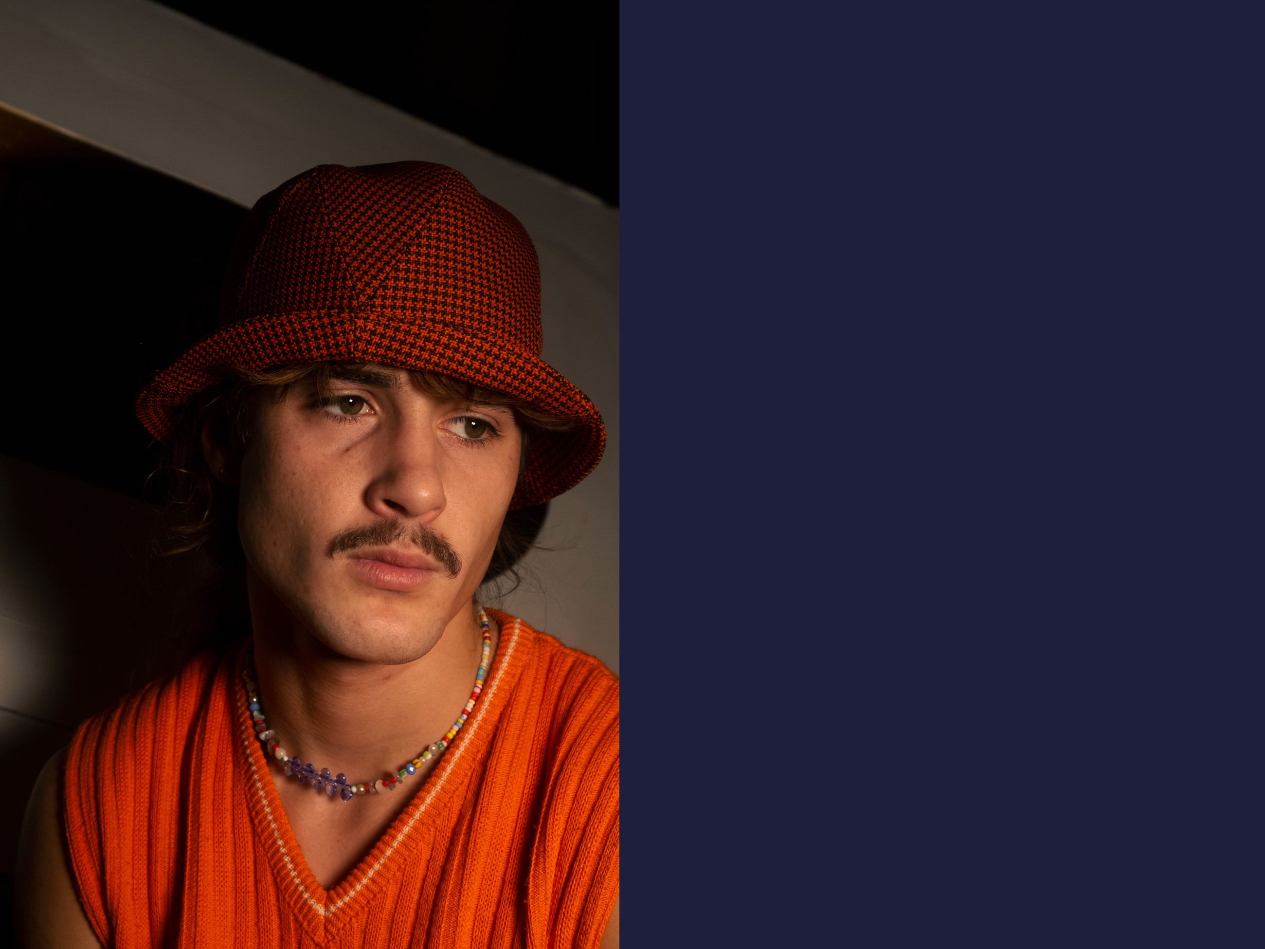 Paul is wearing a Le Panache Paris© bucket hat made in France with Go Couture_63080, Gabriel© brand fabric, 100% Trevira cs, brown houndstooth pattern on a orange background.