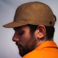 Tristan is wearing a Le Panache Paris© cap made in France with tobacco and ivory stripeweave100% cotton.
